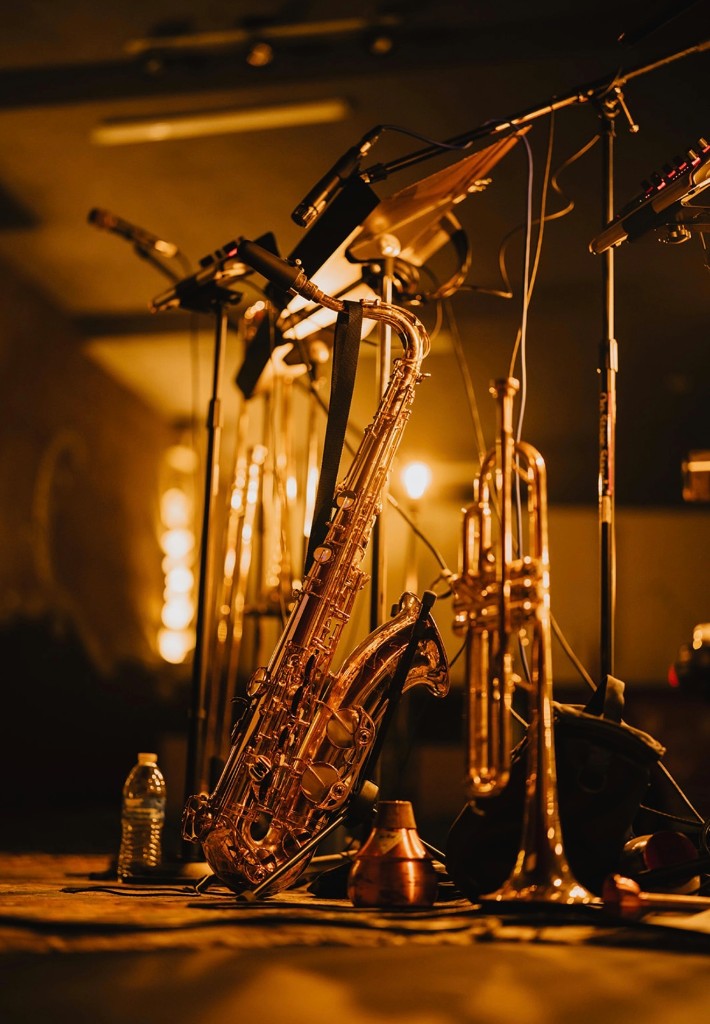 Saxophone and trumpet on stands under warm amber stage lighting